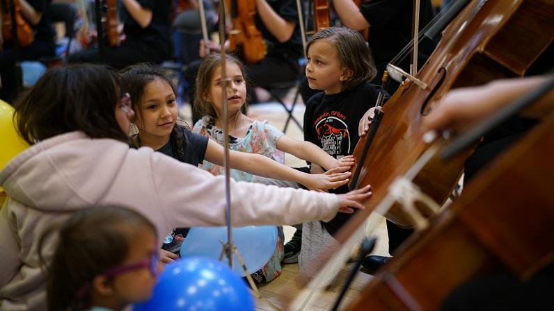 Five students touch a cello to feel the vibrations
