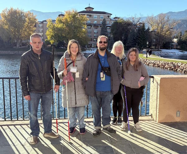 Four students and a teacher standing in front of the Broadmoor Hotel