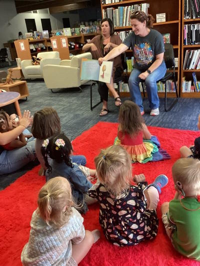 The librarian reads to a group of students sitting on a rug.  An interpreter signs the story.