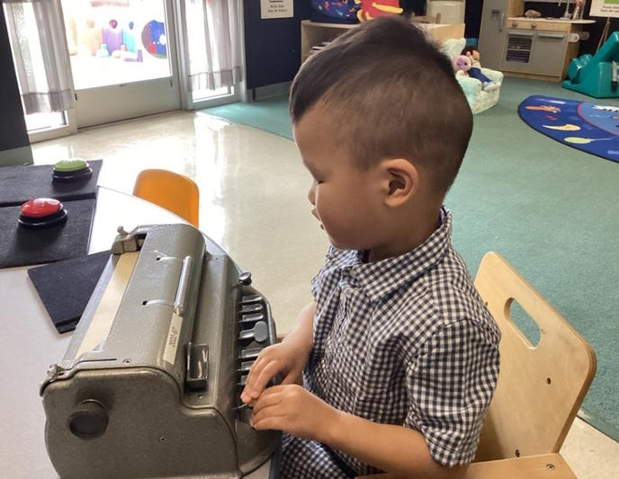 A student sits and uses a brailler