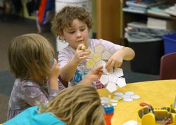  A student holds up a piece of paper divided into multiple sections. She has colored on several with a yellow marker