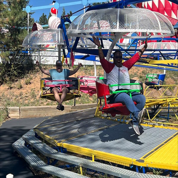 Two teachers ride a ride with their hands in the air.