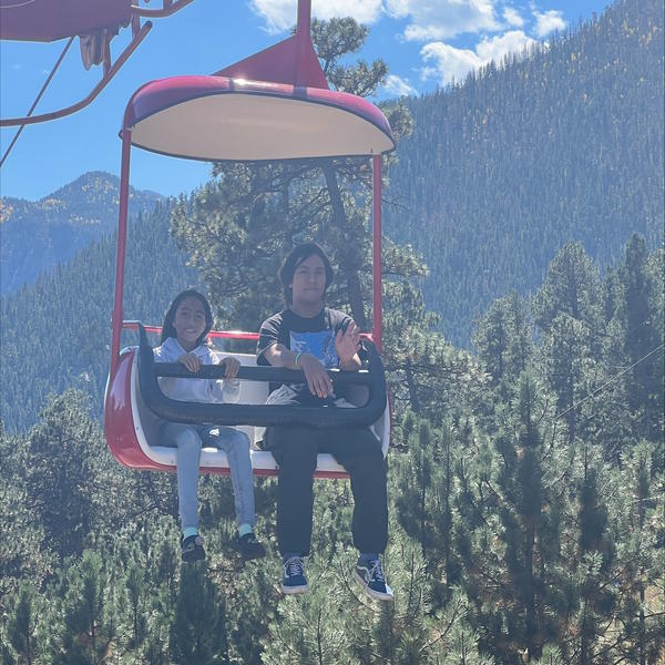 Two students wave to the camera while riding a ride.