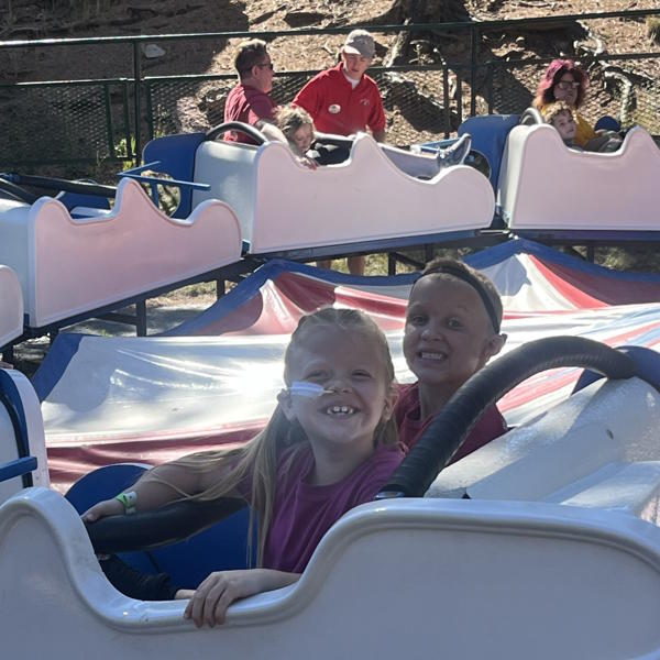 Two student smile at the camera while on a ride.