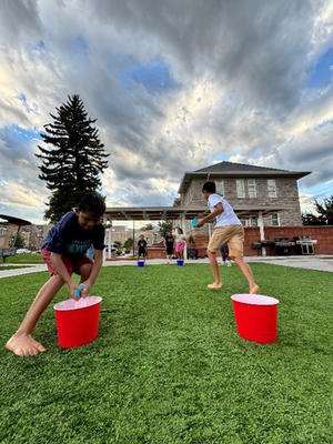 Two students filling balloons with water in a bucket