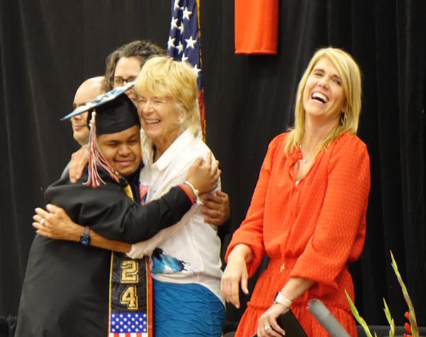 Andre give a hug to guest speaker Jeanette Scheppach while receiving his diploma
