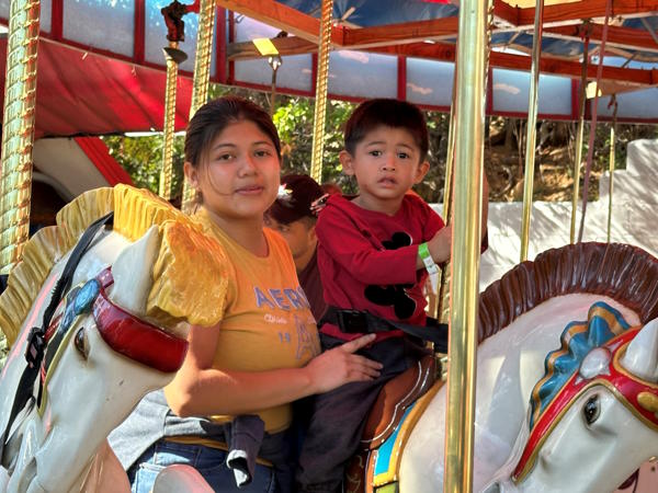 A mom and her son ride a horse on a carousel 