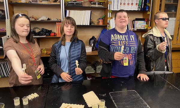 Four students standing and holding rock candy.