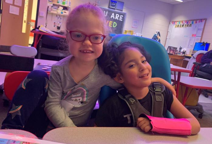 two young girls sitting at a desk looking at the camera