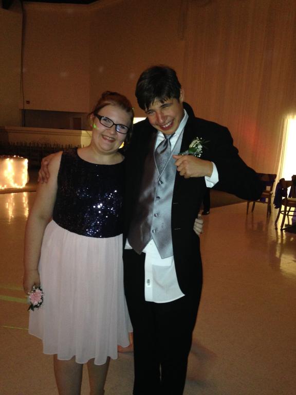Two students standing and smile together at prom.