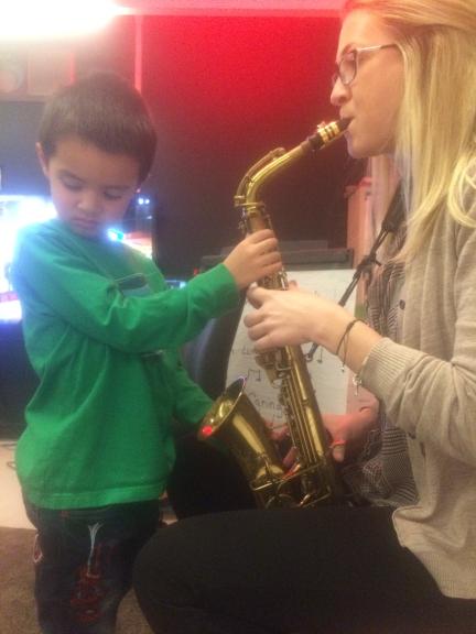 A student feels the saxophone vibrate as a music teacher plays.