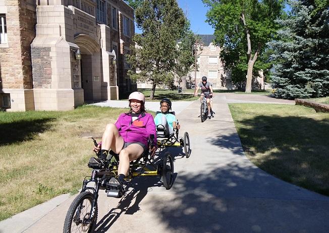 Lady and student on recumbent tandem bike followed by man and student on tandem