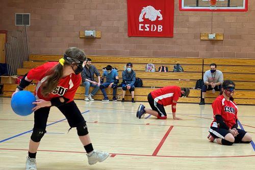 2021 Goalball Staff versus student game, player sets up to throw the goalball across the court.