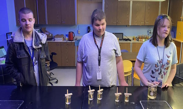 Three students standing at a table making rock candy.