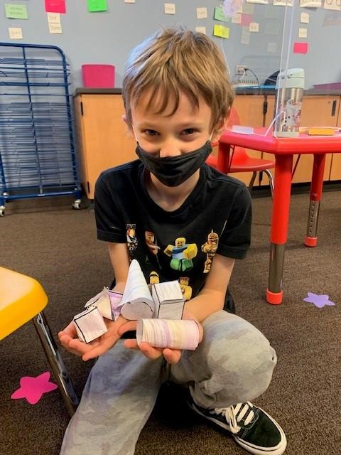 Young boy holds paper-made shapes in his arms