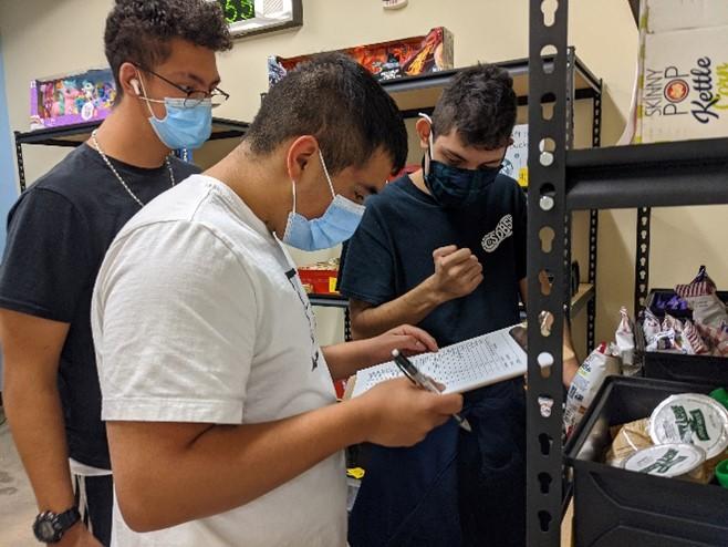Three male students inventory the PRIDE store contents