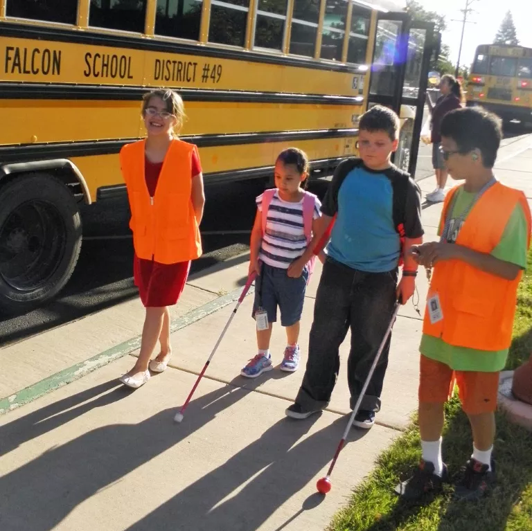 The bus buddies are helping elementary students walk from the buses to the School for the Blind building.