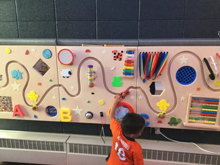 A student explores an interactive wall with various sound and tactile panels.