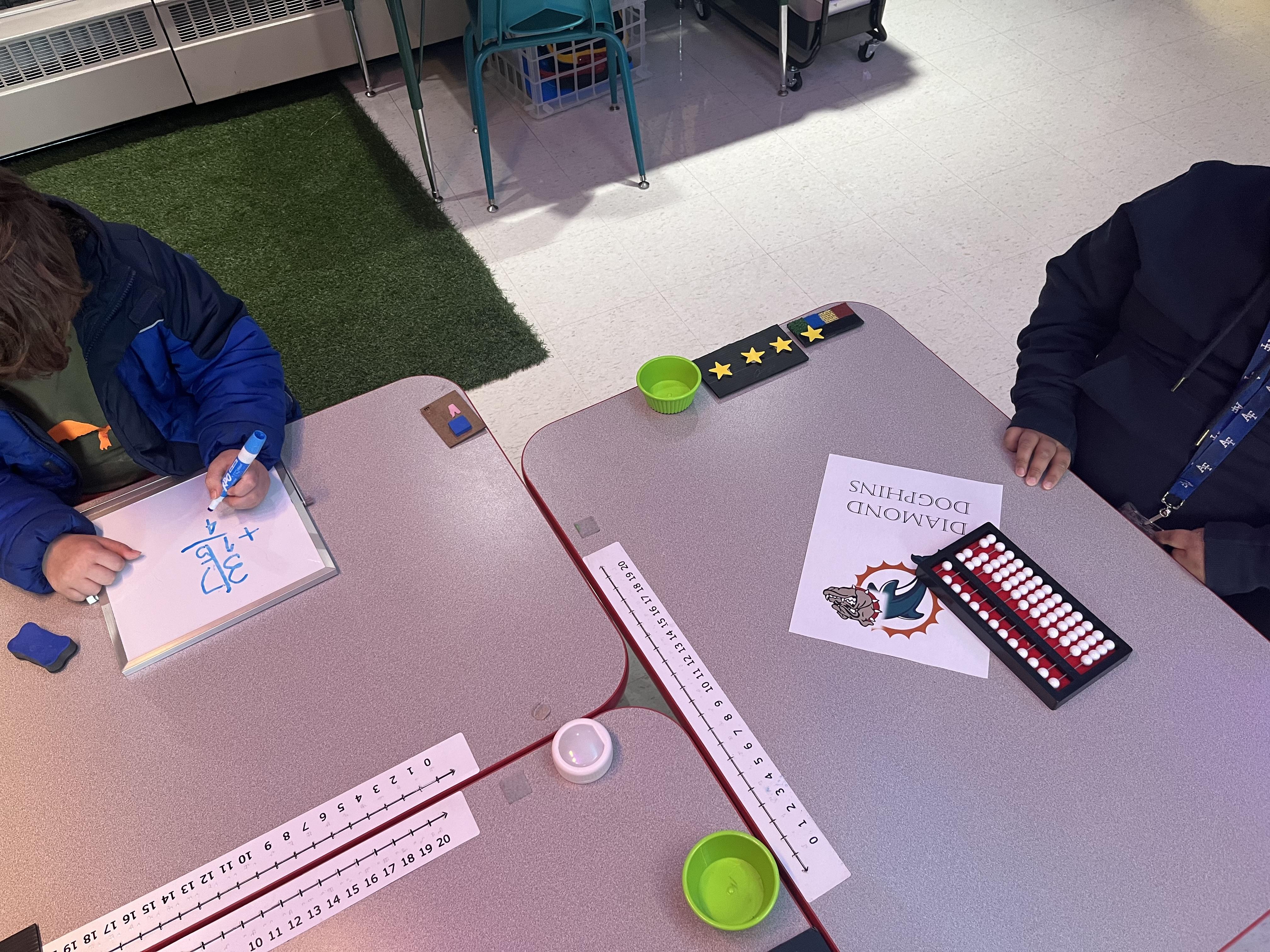 Students practicing math with a whiteboard and an abacus