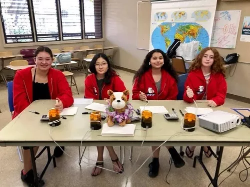 Four students from the Academic Bowl sitting at a table ready to compete in Hawaii classroom.