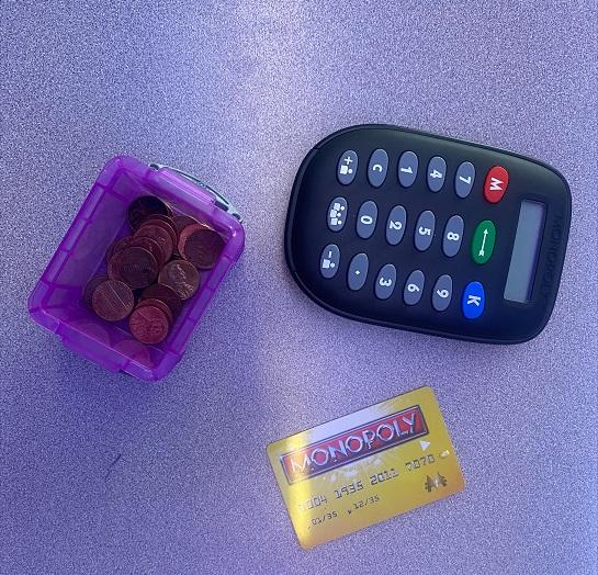 Three items: a box of coins, a Monopoly credit card, a calculator