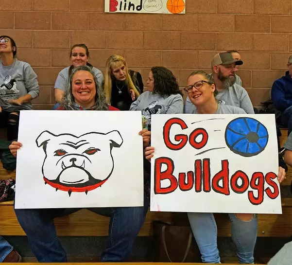 one lady holds a hand-drawn Bulldog next to another holding "Go Bulldogs" sign