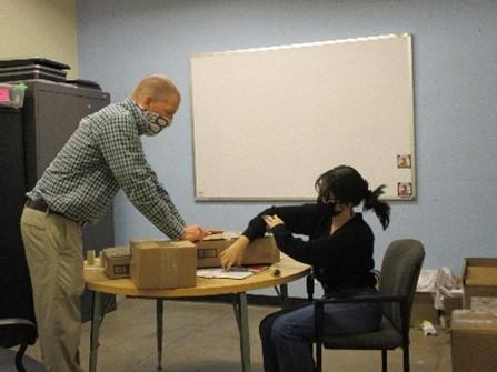 older female student and male teacher tape boxes together in the classroom