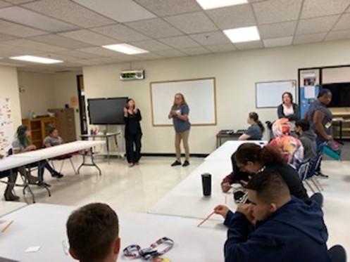 A woman from the Habitat for Humanity ReStore presenting to Deaf/Hard of Hearing and Blind Visually Impaired students seated in an Employability Center classroom 