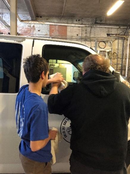 Older student and male staff working on a van