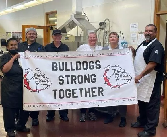 kitchen staff holding a banner that reads Bulldogs Strong Together
