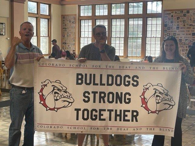 staff holding a banner that reads Bulldogs Strong Together