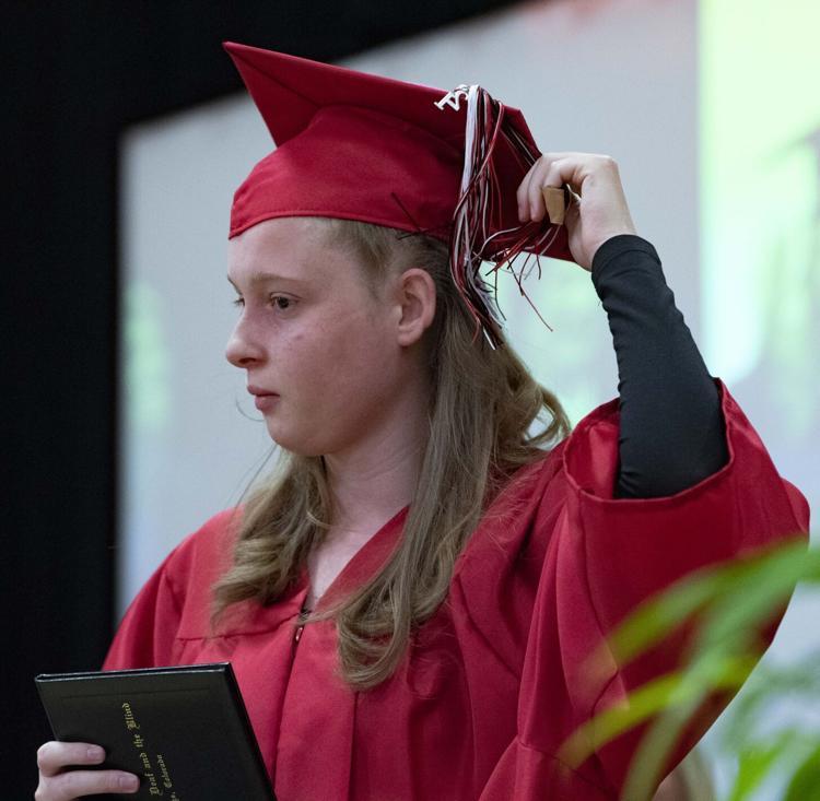 Graduate holds diploma and touches hat