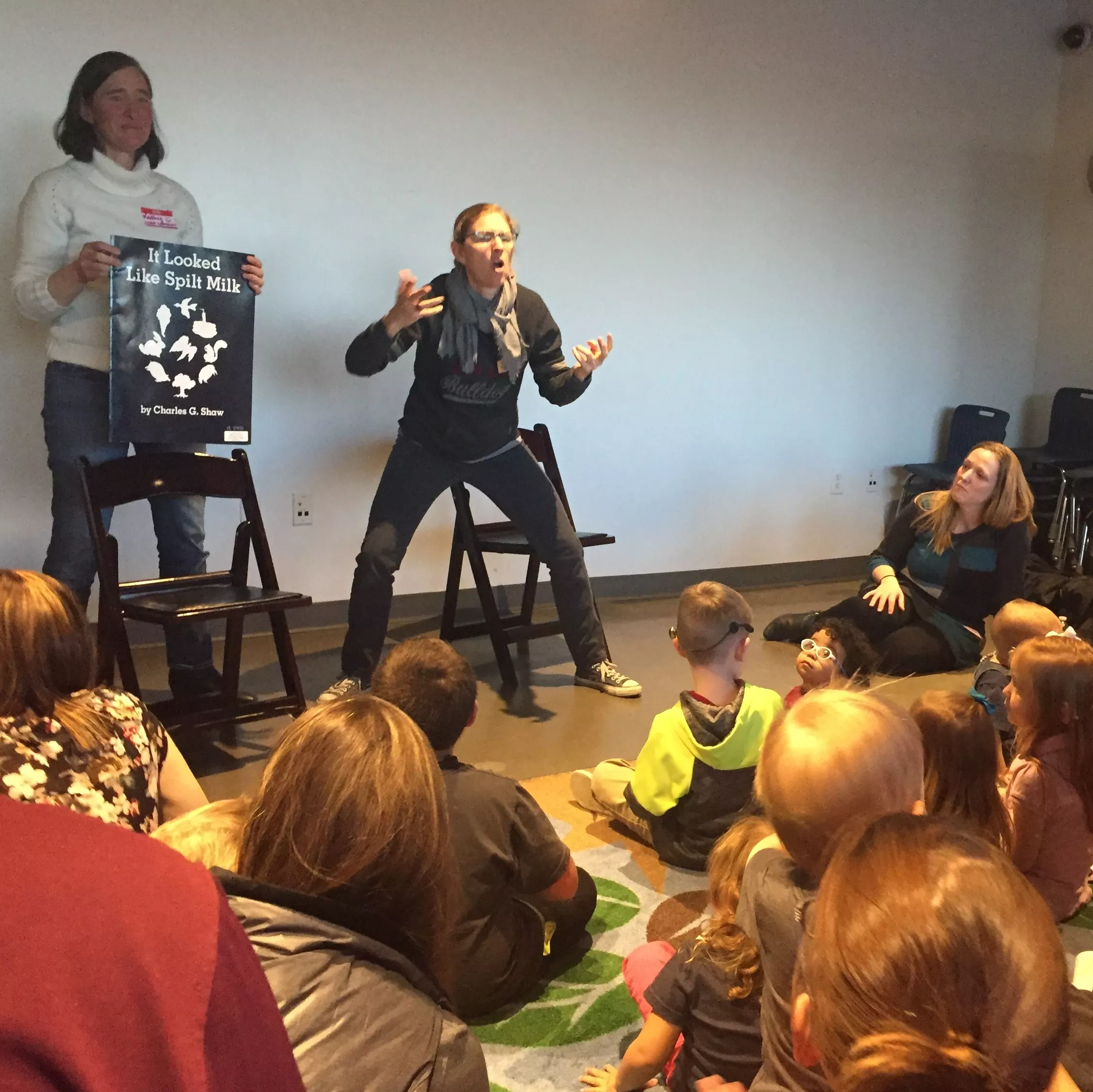 A woman is telling a story in ASL for an audience of children and adults.