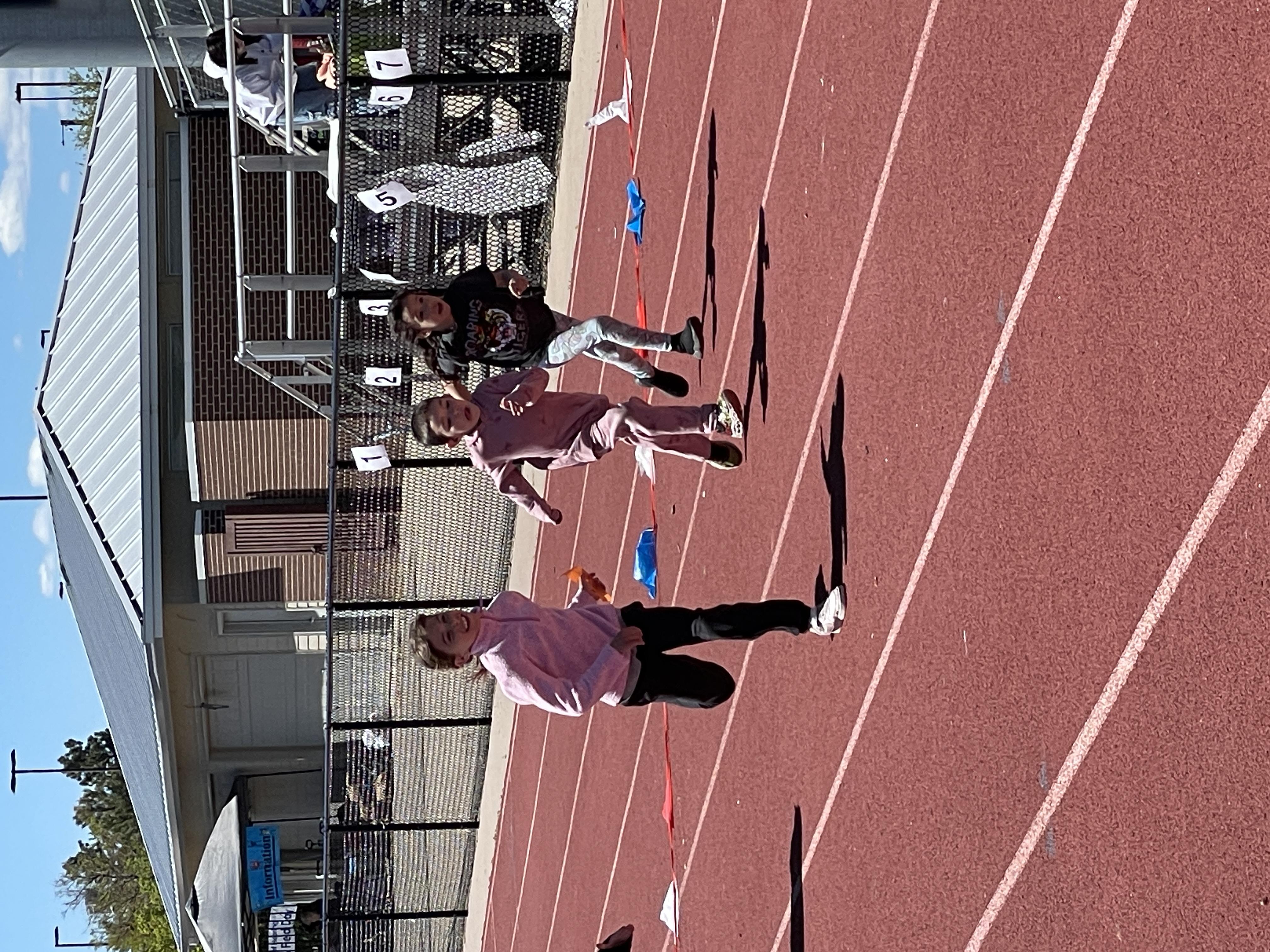 Three youth sprint in their lanes on a track