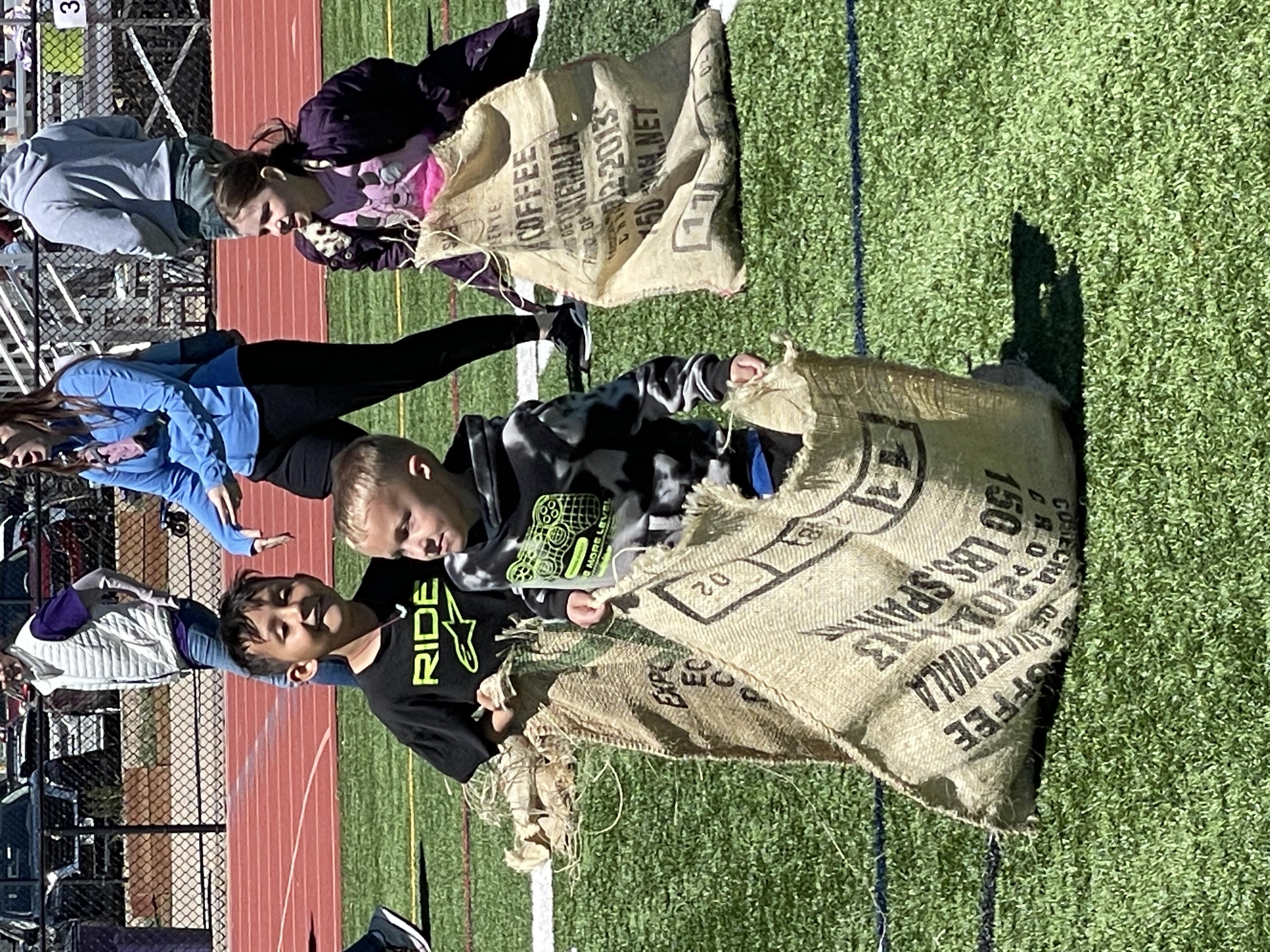 three youth each in a gunny sack, hop on the grass