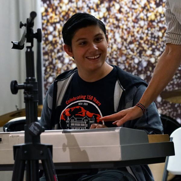 Student sits at a piano and plays