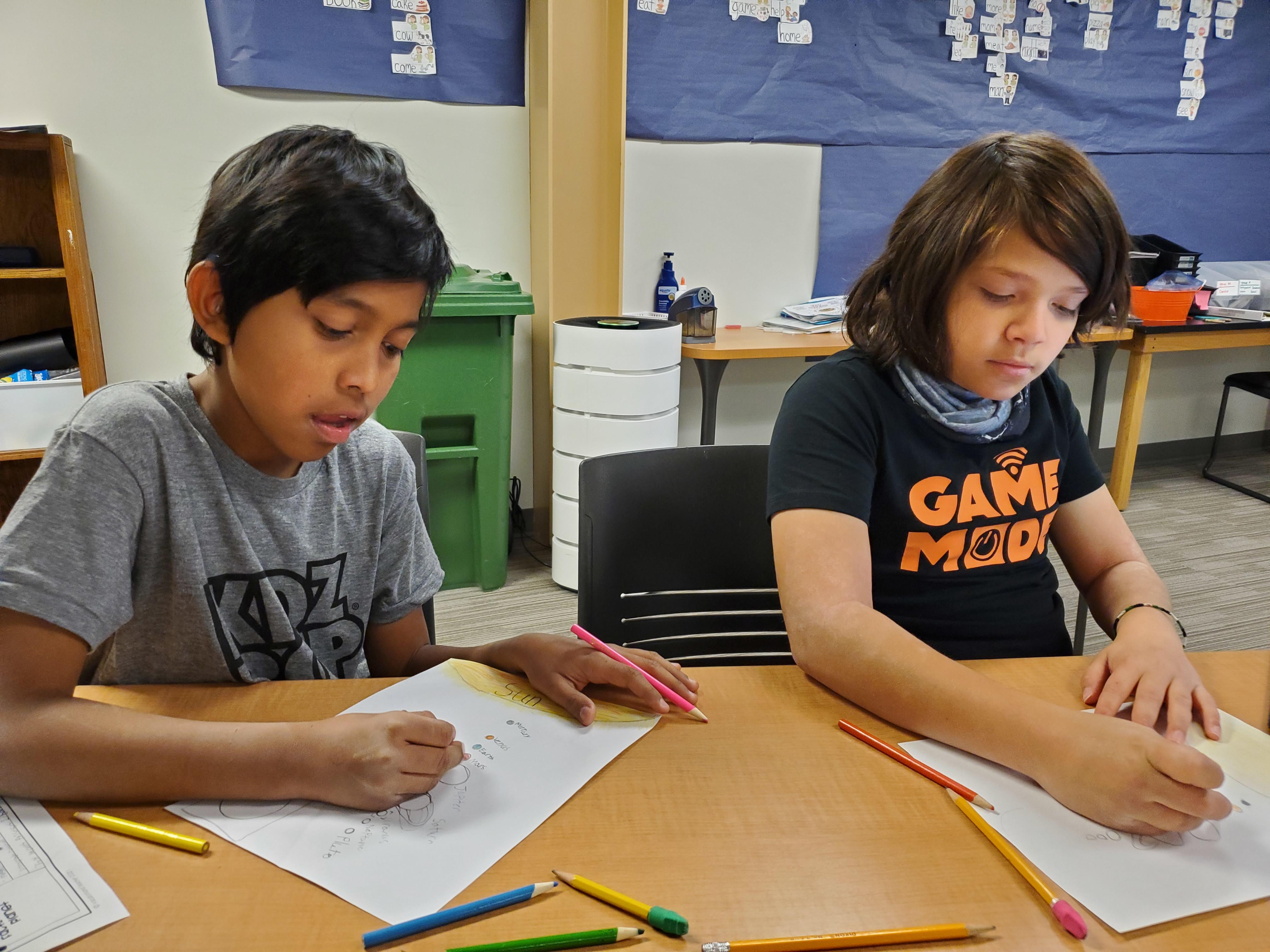 two boys writing at the classroom table