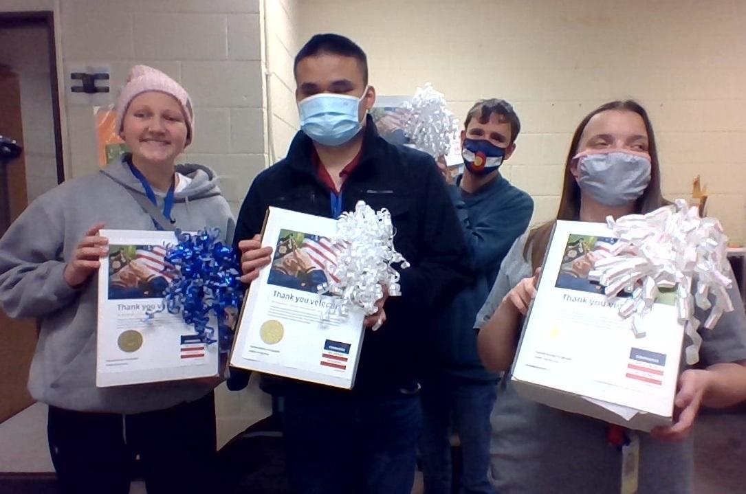 Four students hold gifts wrapped with bright bows