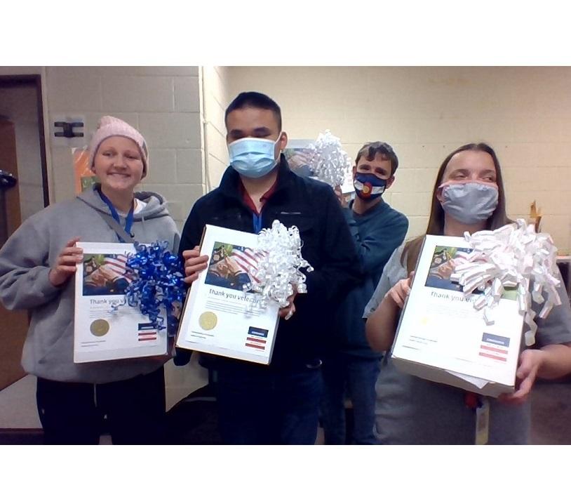 4 students holding decorated boxes that read “Thank you veterans!”