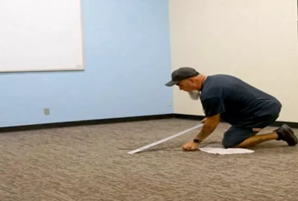 Facilities employee installing new carpet