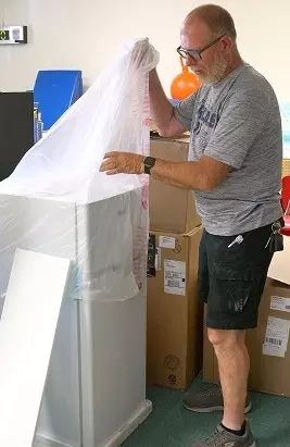 Facilities employee unwrapping new refrigerator