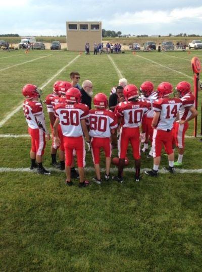 The football team is huddling with their coaches during a game