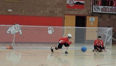 Athlete competing in Goalball game, center throws the ball down the court.