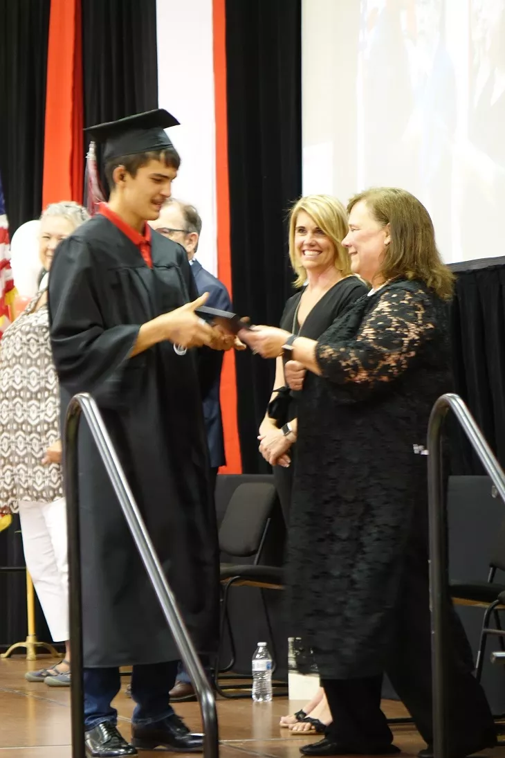 Superintendent hands grad his diploma