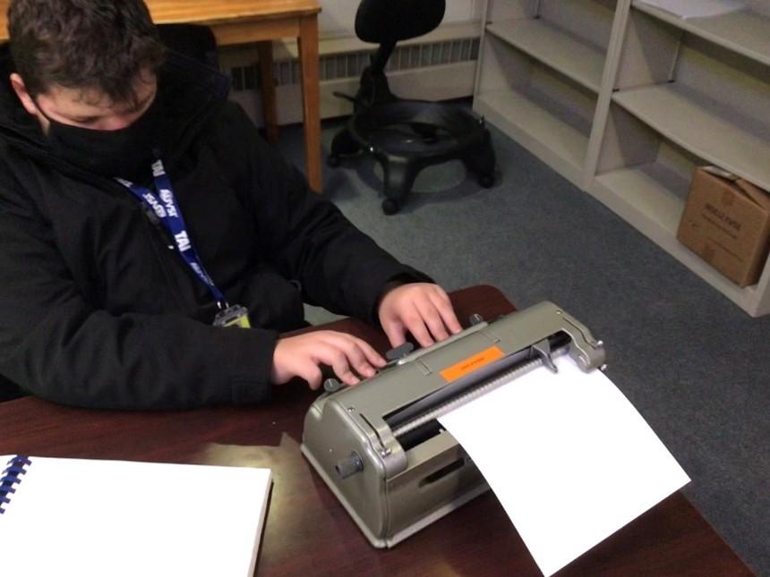 boy uses a brailler to type
