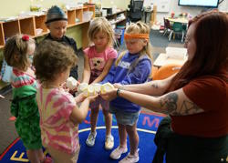 Five students and a teacher form a circle and hold their orbs in the center.