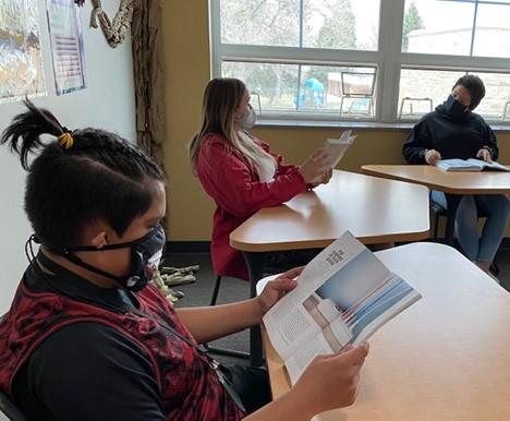 Three students reading at their classroom desks
