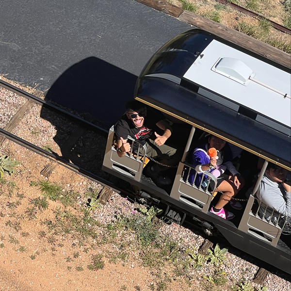 Teachers and students ride a train and look up at the camera.