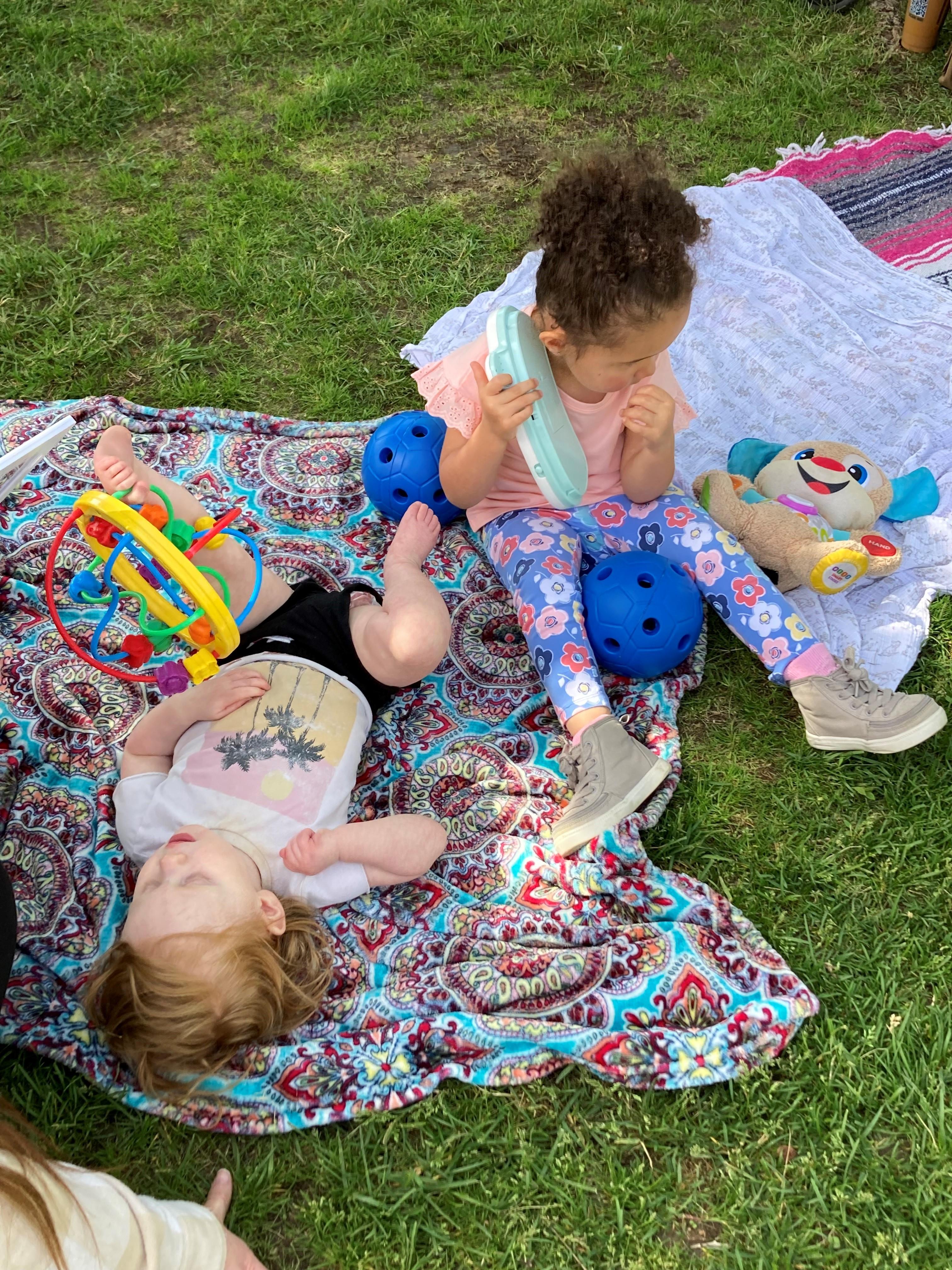 Two young children on blankets on the grass