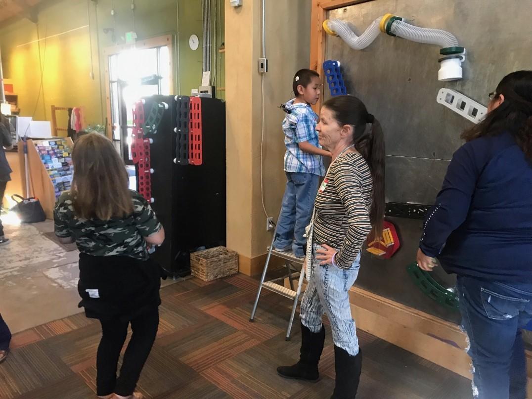 Ladies watch children while one stands at the ball wall